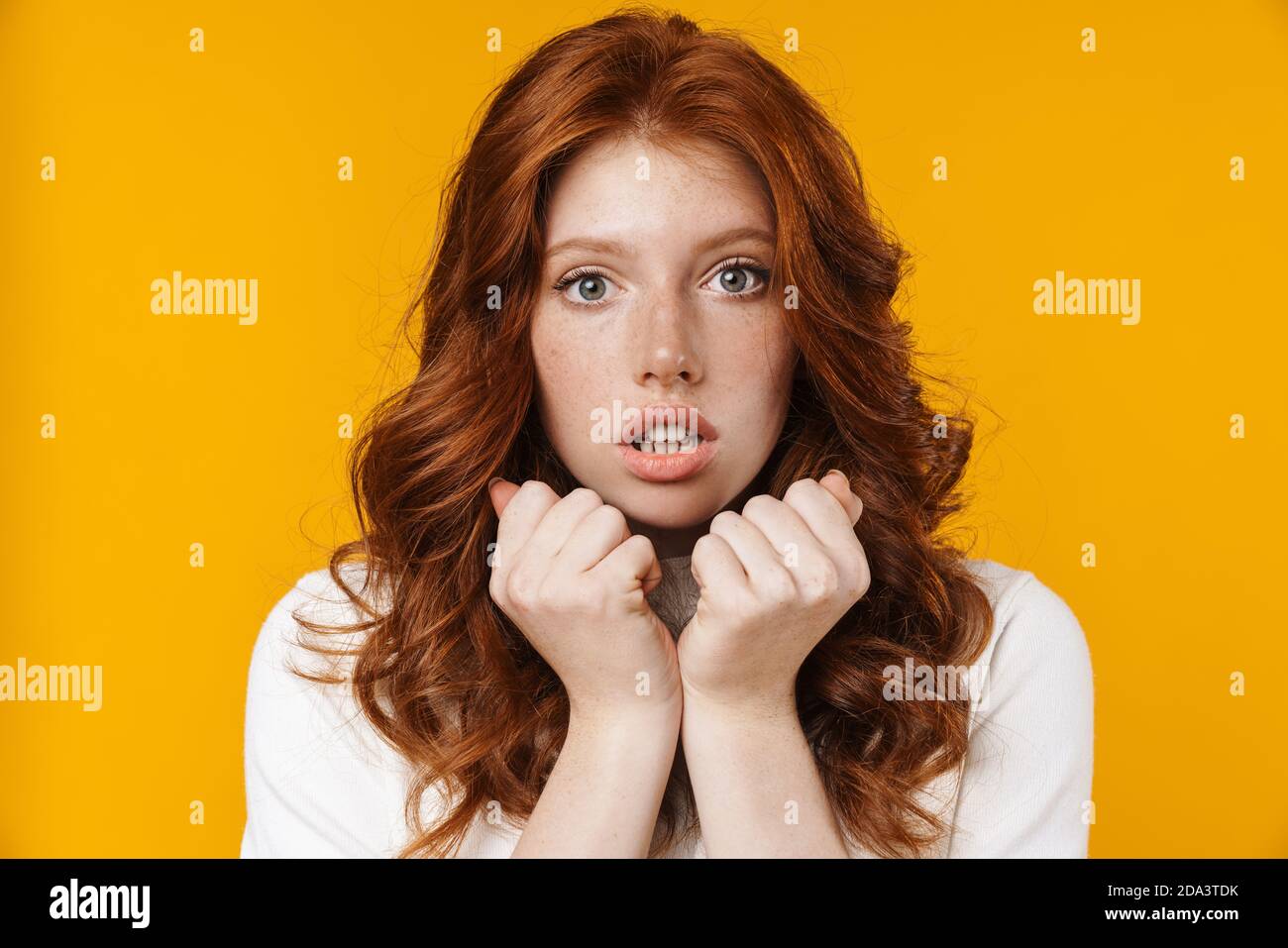 Image of ginger scared girl posing and looking at camera isolated over ...