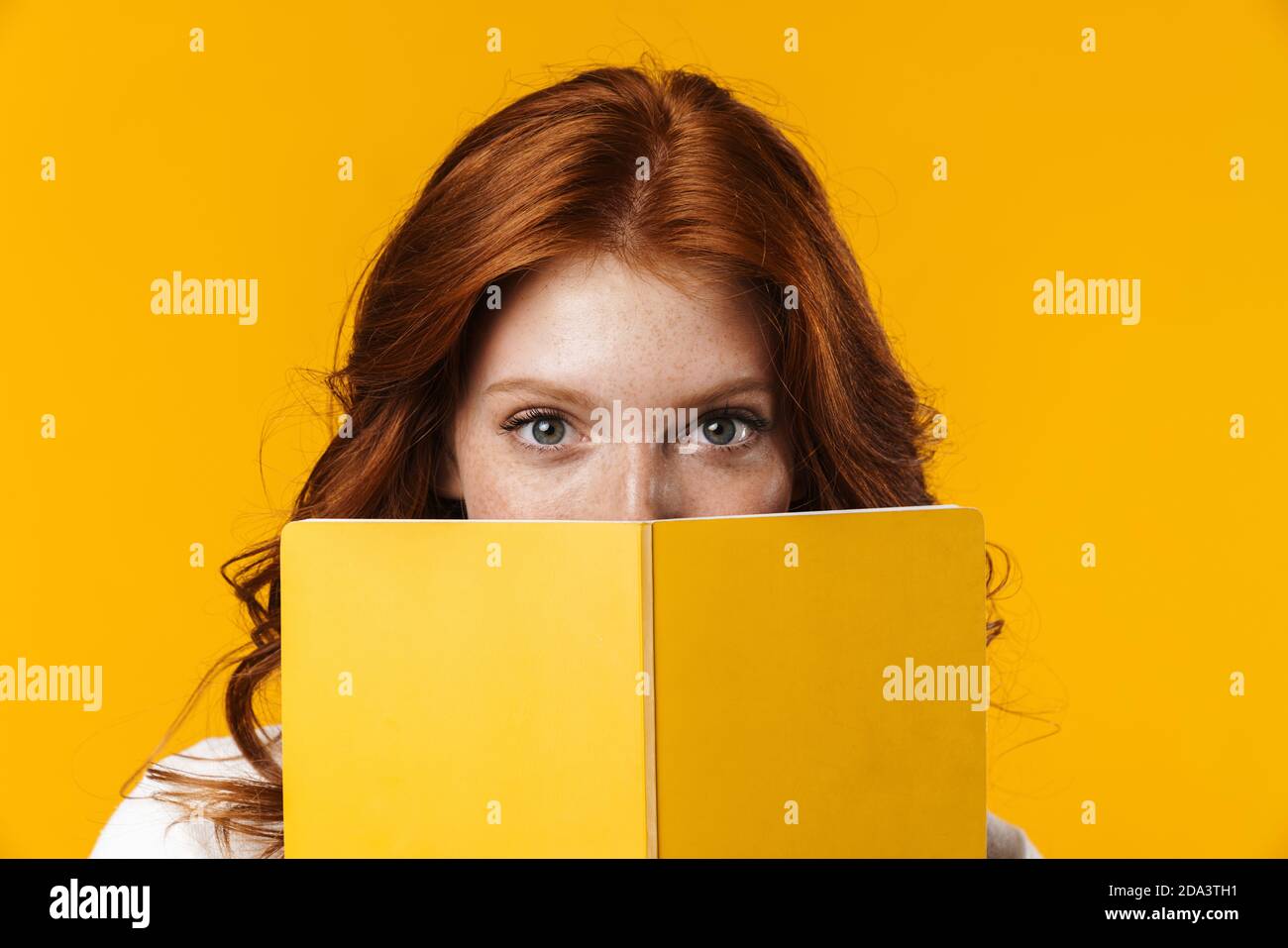 Image of ginger beautiful girl looking out for exercise book isolated ...