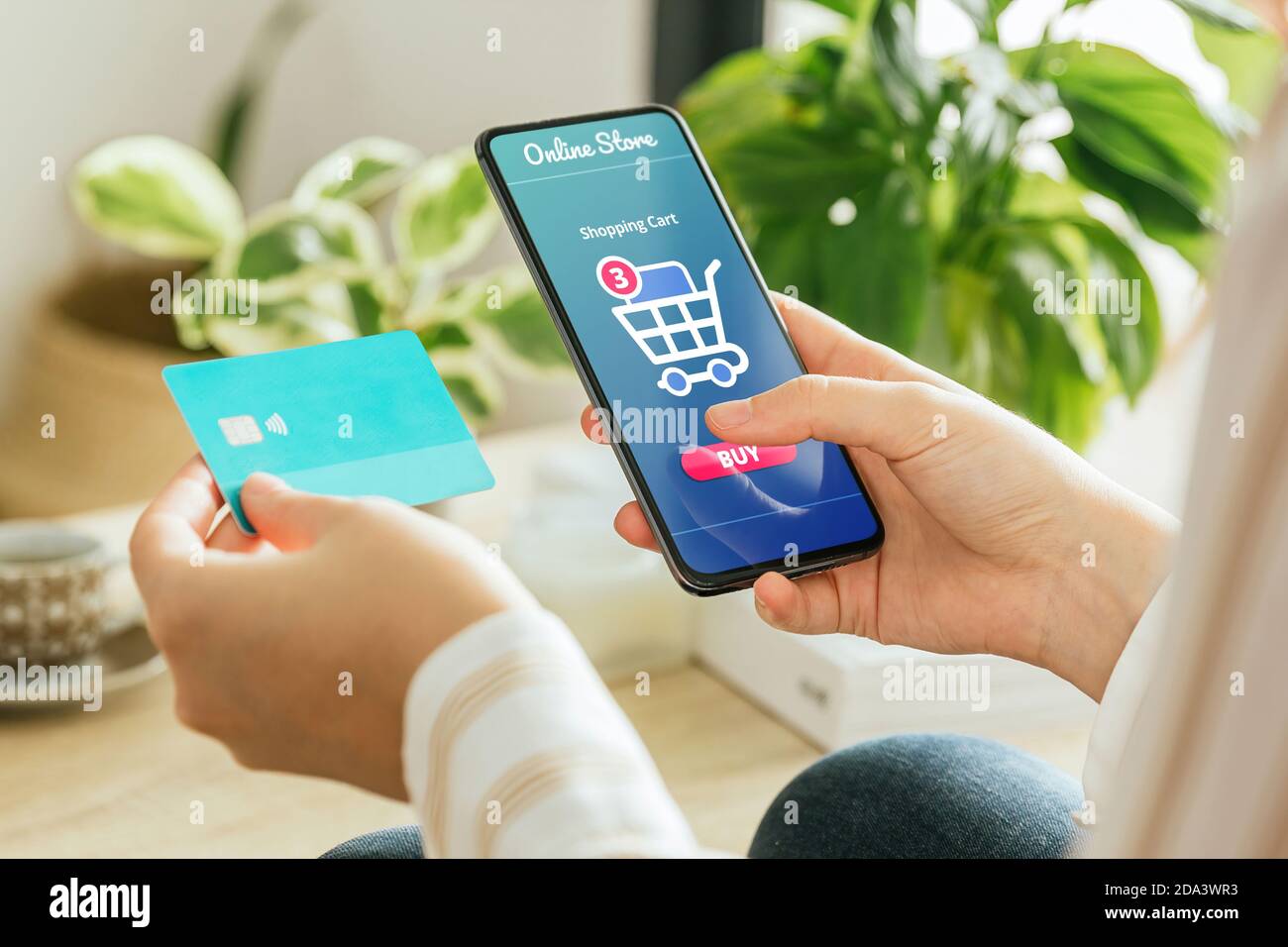 Mockup of a woman paying an order online with the phone and a credit card from home. E-commerce concept Stock Photo