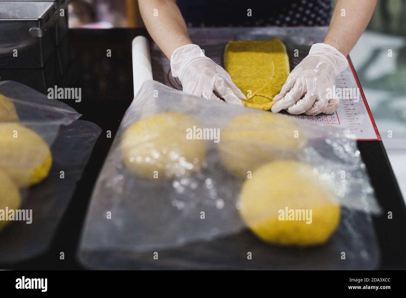 Womens hands roll out the pumpkin bread dough on kitchen table. Stock Photo