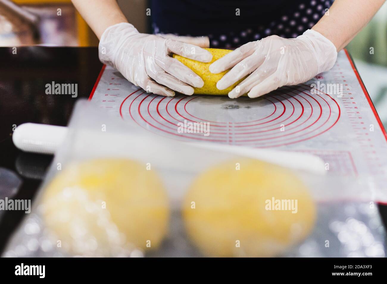 Womens hands roll out the pumpkin bread dough on kitchen table. Stock Photo