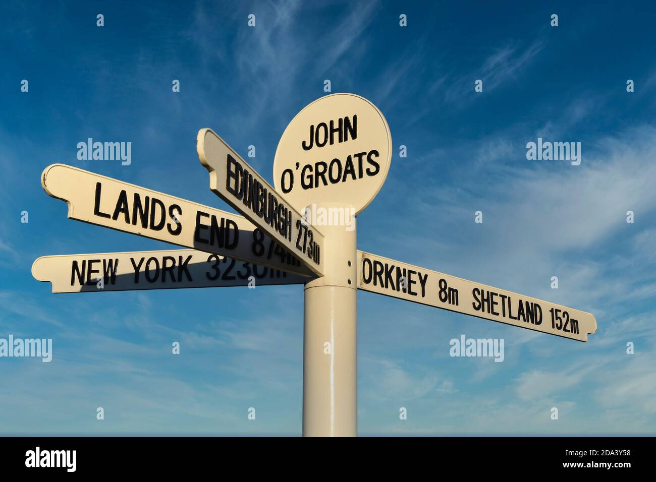New John O'Groats sign with mileage to Orkney, Shetland, Lands End, Edinburgh and New York. Isolated against blue sky and light cloud background Stock Photo