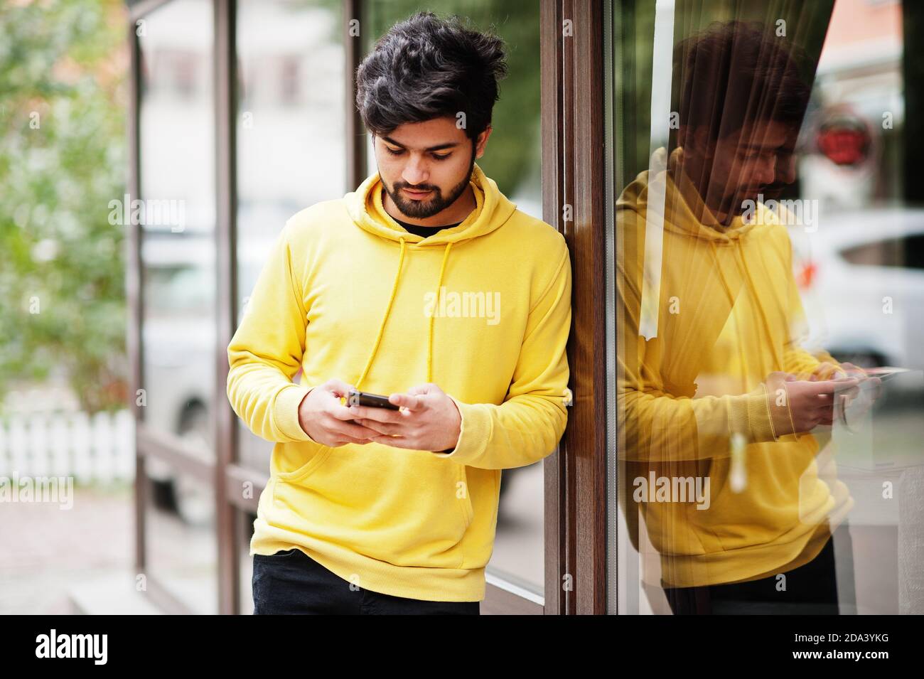 hombre indio joven hipster urbano en una sudadera amarilla de moda. Un  chico genial del sur de Asia usa una sudadera con capucha caminando en Fall  Street. 11017100 Foto de stock en