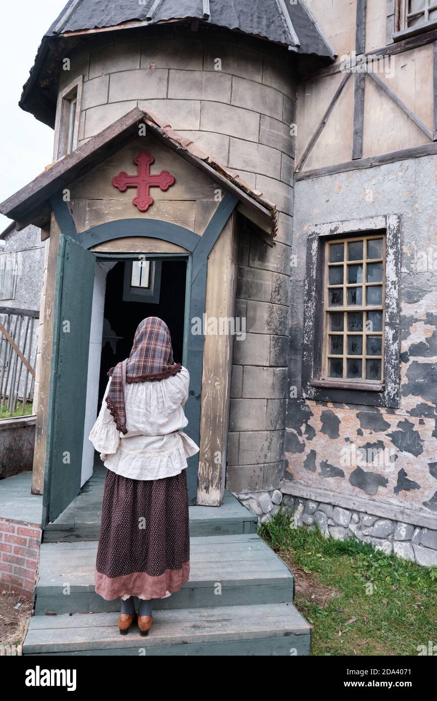 A girl parishioner in a headscarf and medieval clothes at the door of a retro American Church Stock Photo