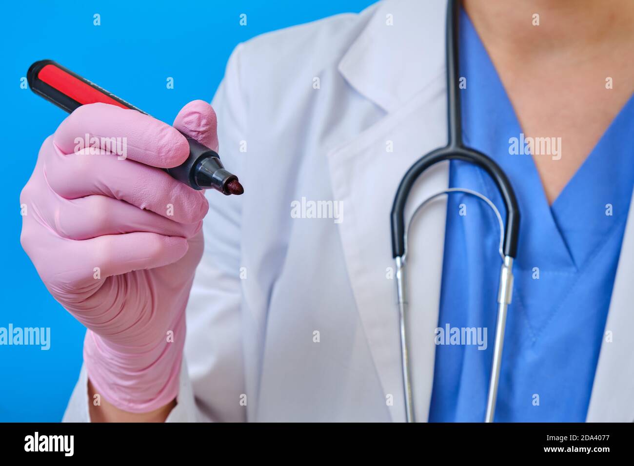 Doctor with a marker in hand, close-up. A nurse in a medical uniform writes  with a pen, blue background Stock Photo - Alamy