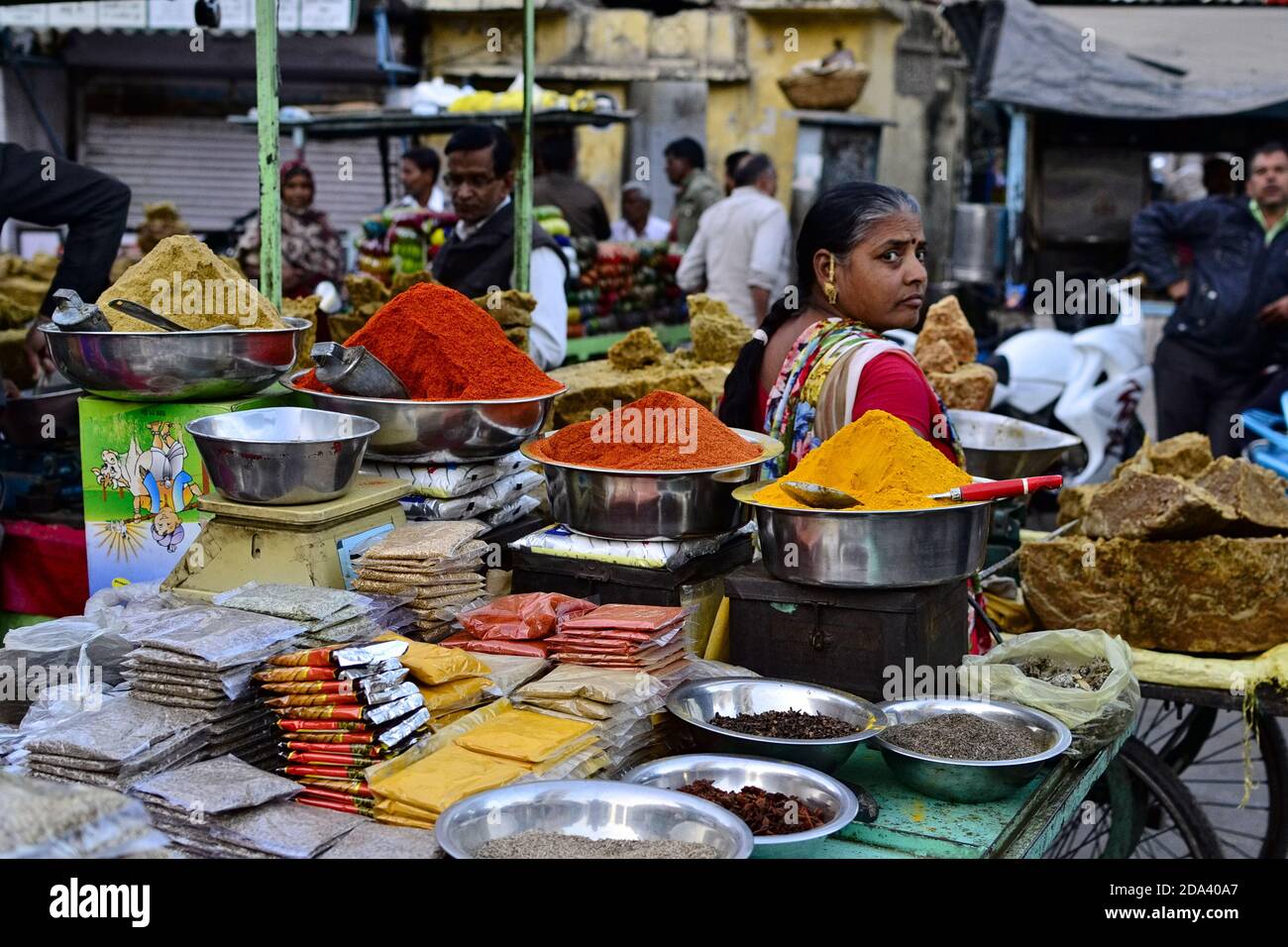 Udaipur, Rajasthan, India - December 2016: Indian woman sells colorful spices (curcuma, curry, chili pepper powder) on the traditional street market Stock Photo