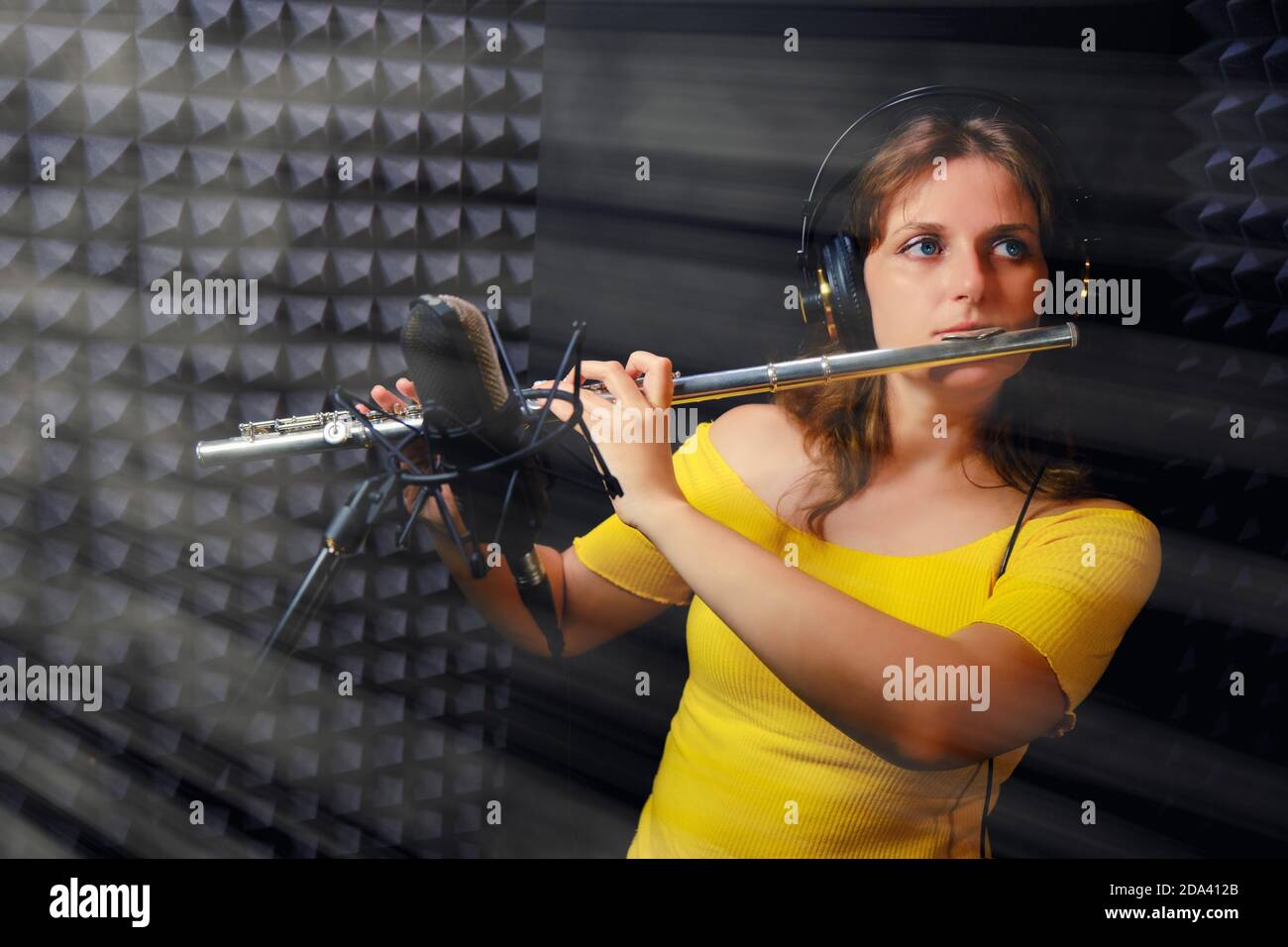 Female flute player plays in recording studio. Woman flutist in