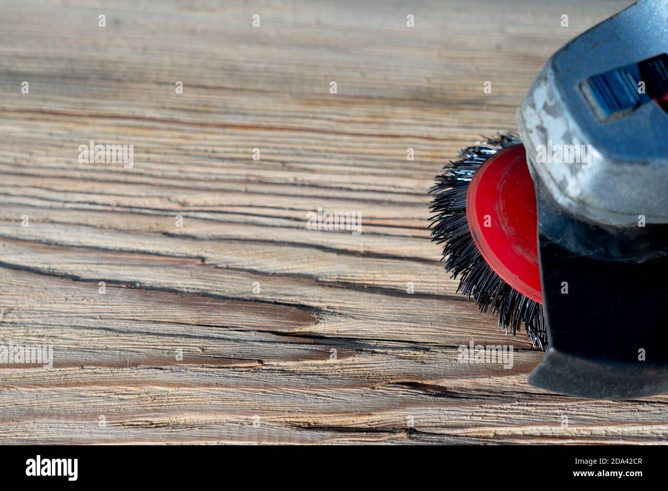 Electrical rotating brush metal disk sanding a piece of wood Stock