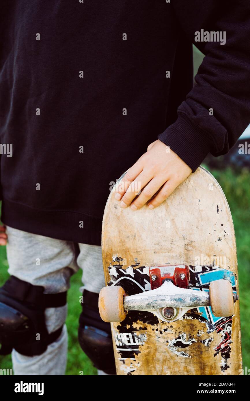 Close up of an skater boy with an old skateboard in front of a graffiti mural Stock Photo