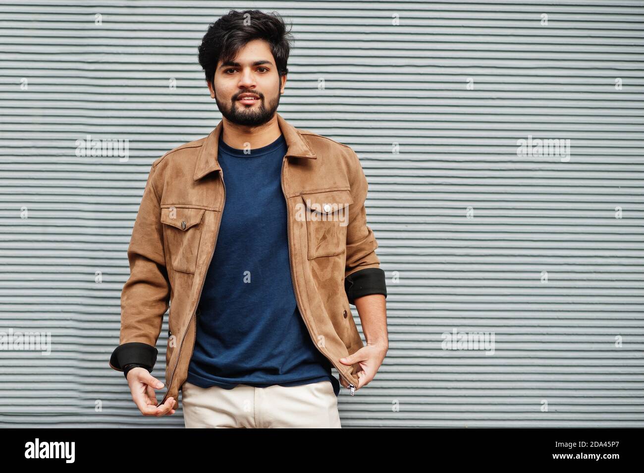 Stylish casual indian man wear blue t-shirt and brown jacket posing against  grey wall Stock Photo - Alamy