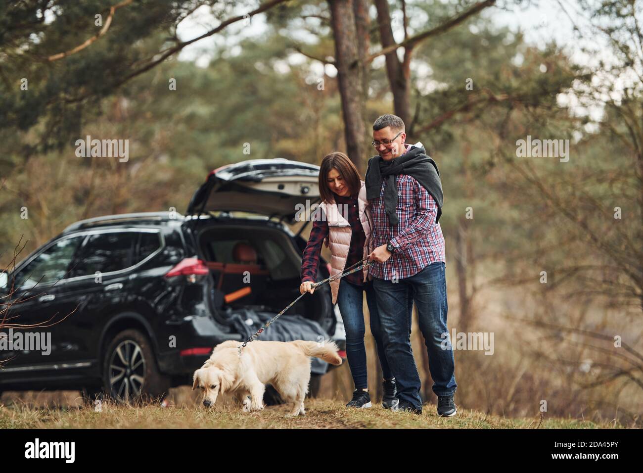 Happy mature couple have a walk with their dog in autumn or spring ...