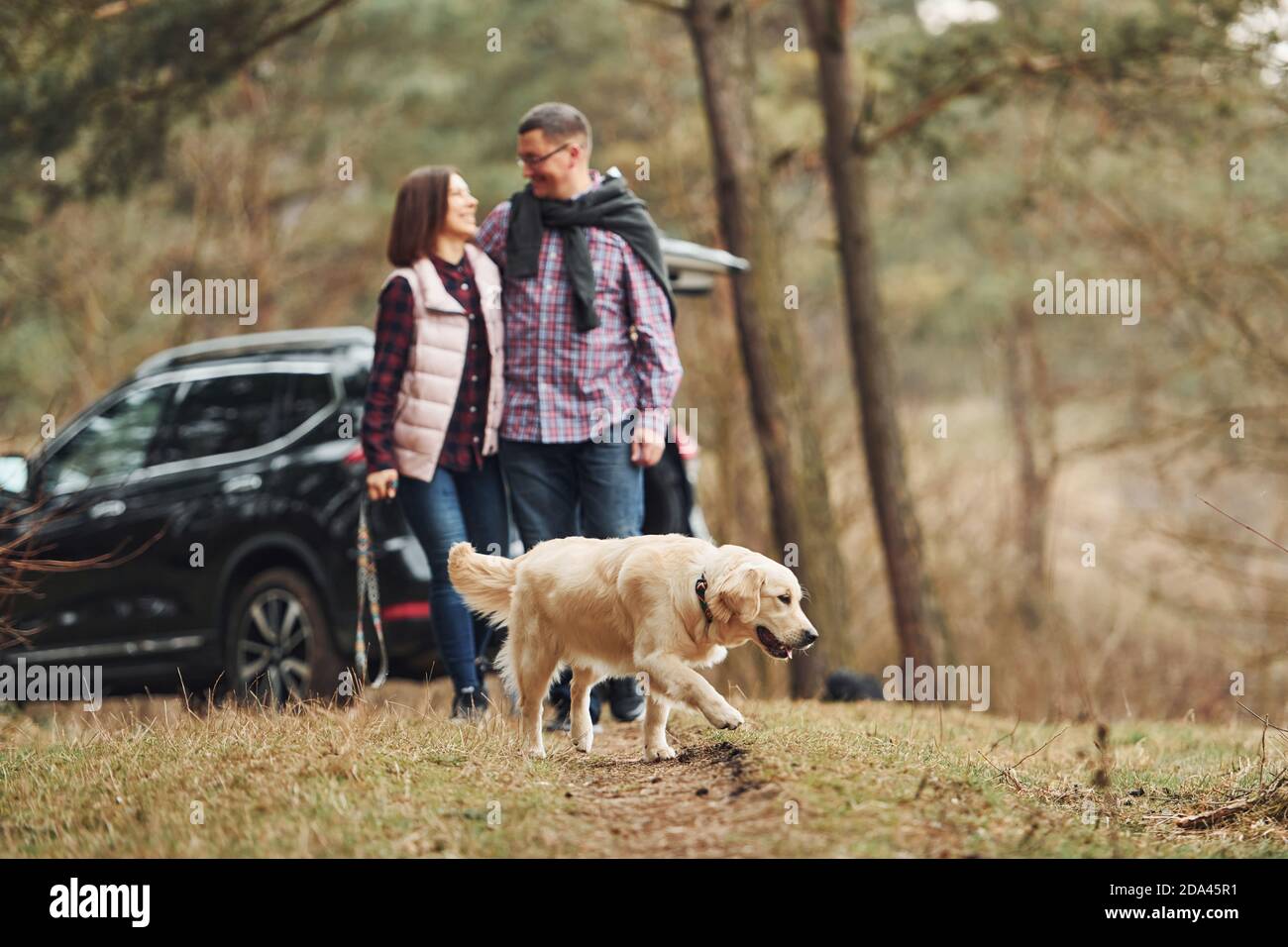 Happy mature couple have a walk with their dog in autumn or spring ...