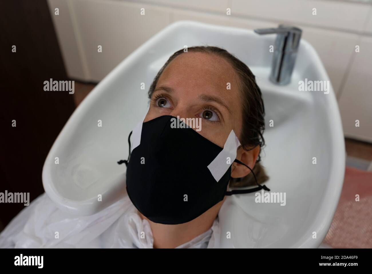 Woman wearing medical protective mask at hairdressing salon.Customers , workers and business measures against coronavirus concept, new normal pandemic Stock Photo