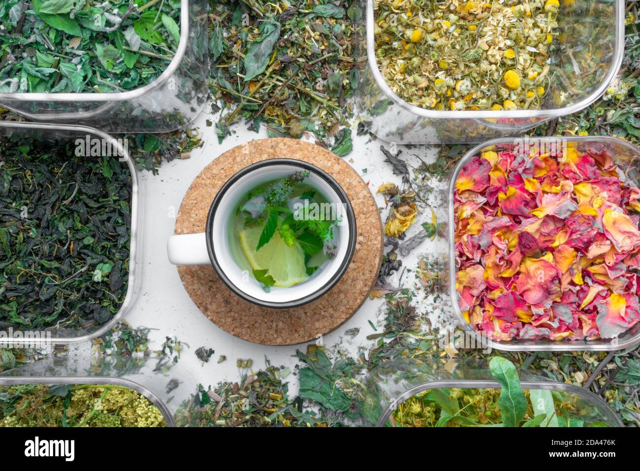 assortment of dry healing herbs and tea in cup with lemon and mint ...