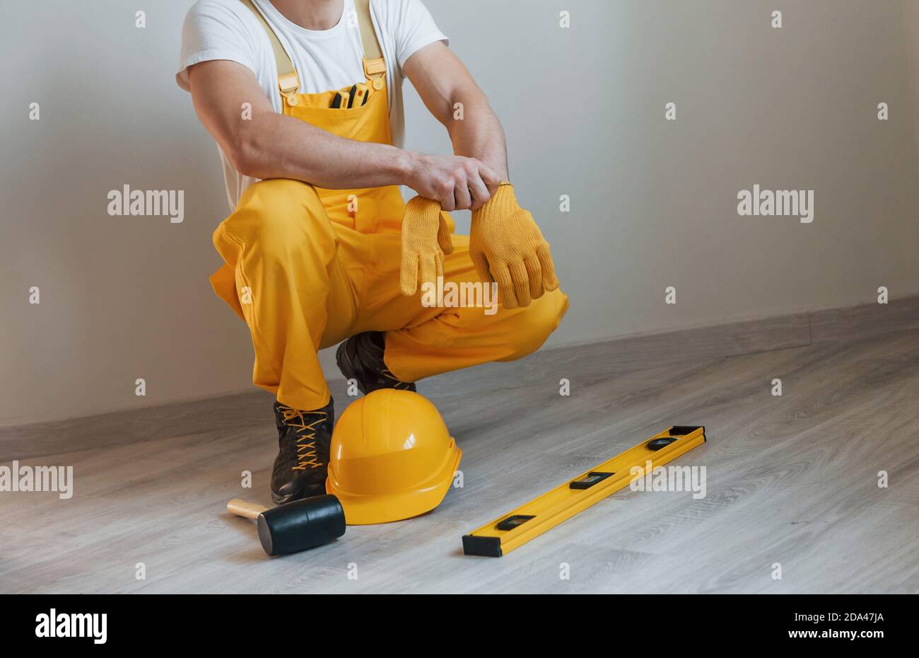 Tools on the floor. Handyman in yellow uniform standing indoors. House renovation conception Stock Photo