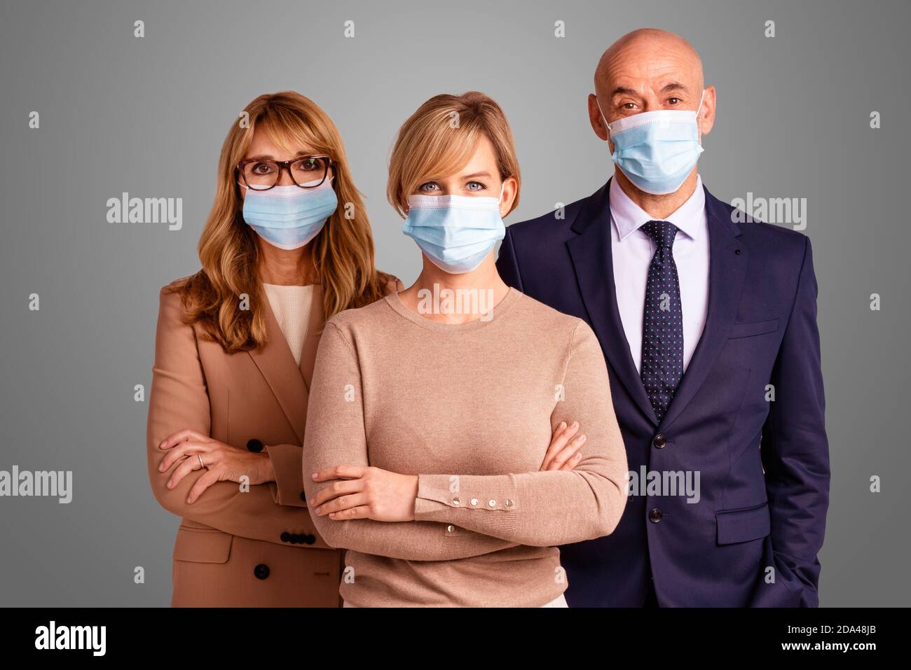 Group of business people wearing face masks and looking at camera while ...