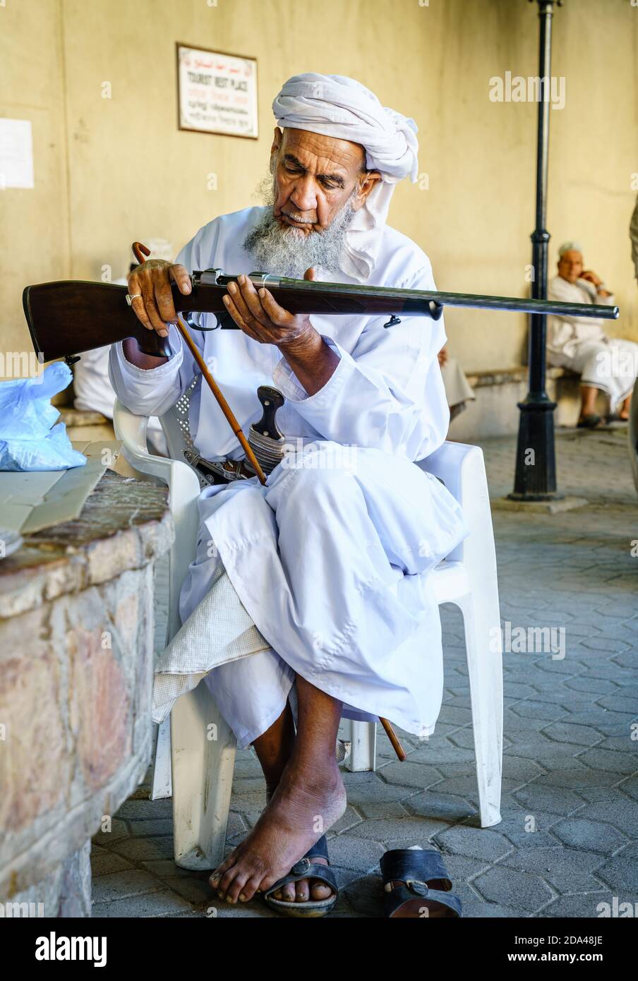 Nizwa, Oman, December 2, 2016: An elderly man is inspecting a hunting rifle at the Friday gun market in Nizwa, Omam Stock Photo