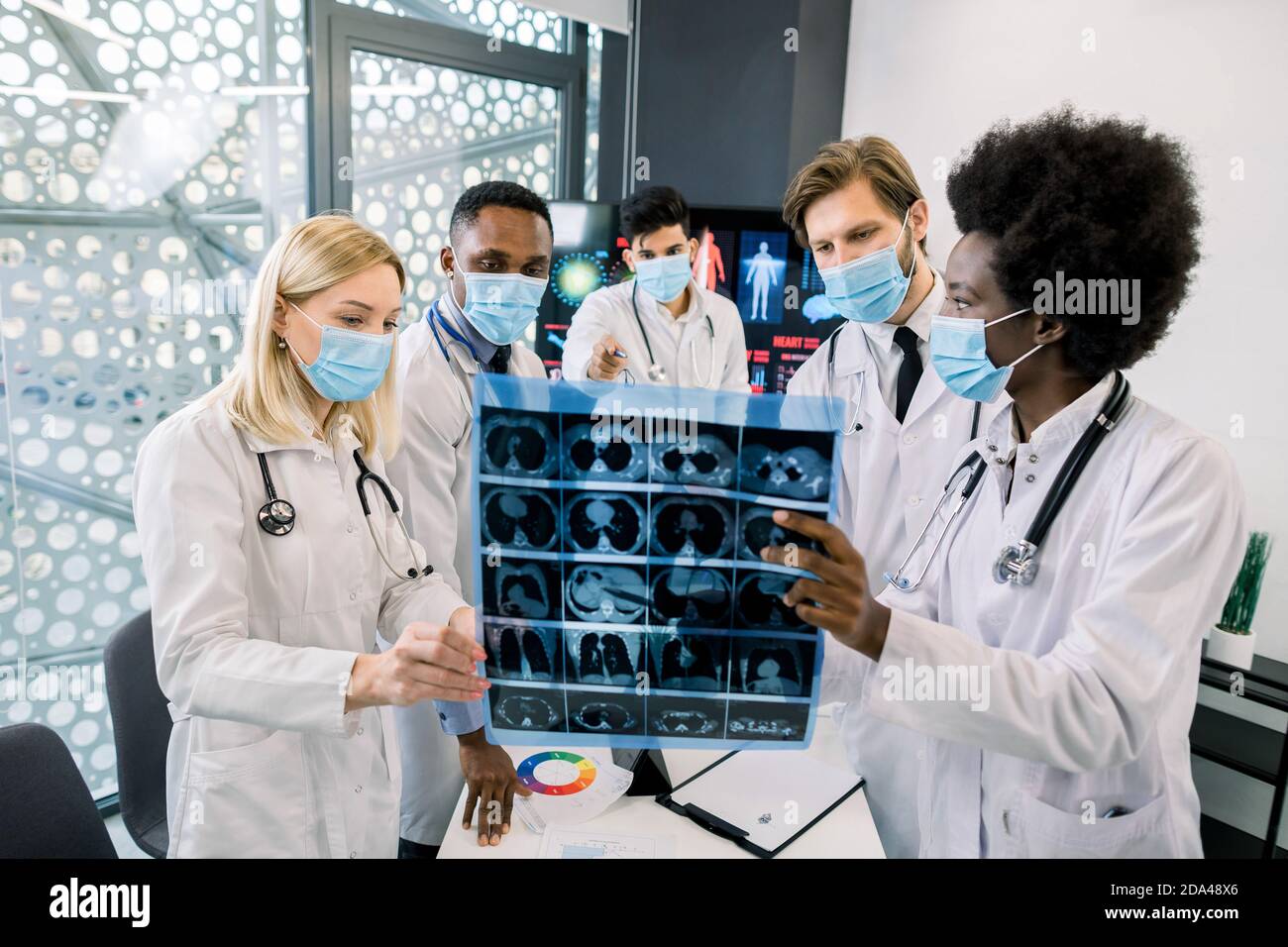 Multiethnical five doctors, wearing lab coats and medical masks