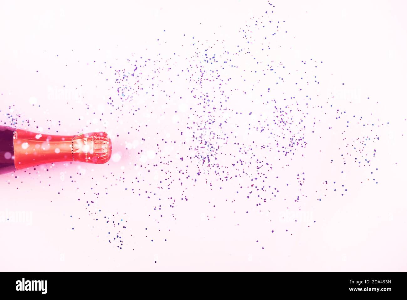 New Year's serpentine flies out of the bottle of champagne, multicolored sequins on a light background. New Year's content 2021. Flat lay Stock Photo