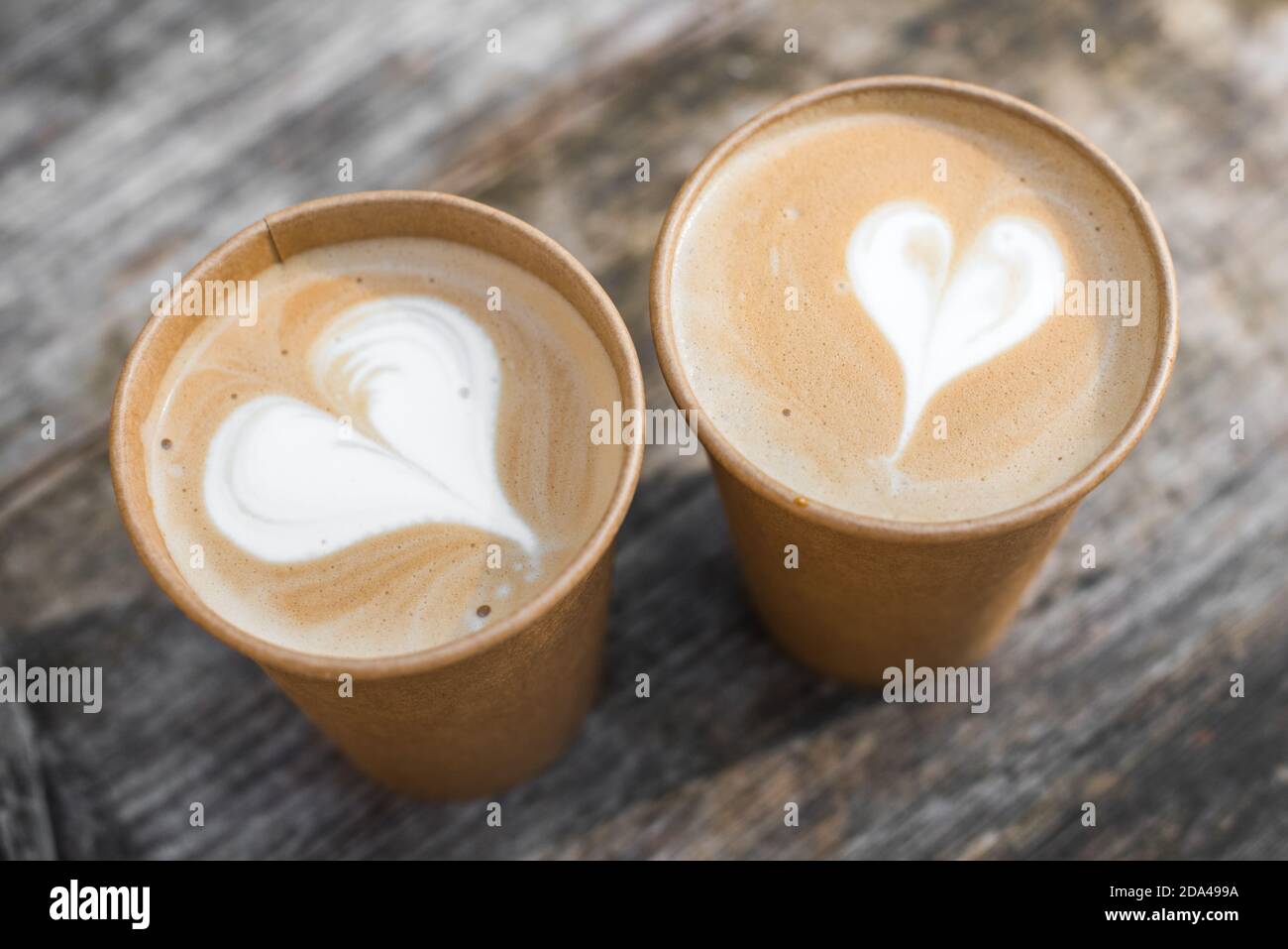 Two paper cups of coffee with heart shape latte art on yellow background  Stock Photo - Alamy