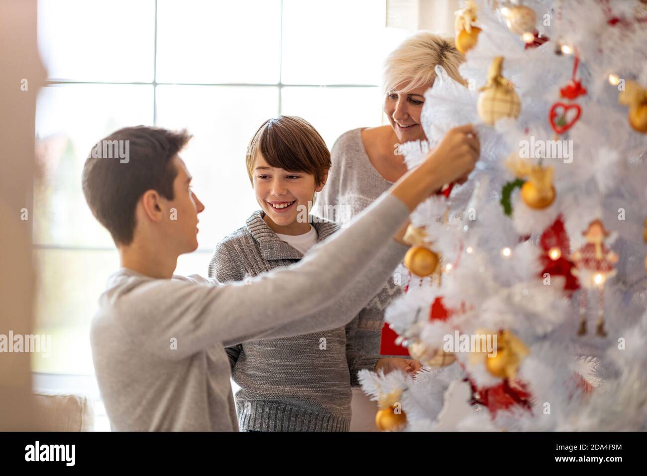 Happy family decorating Christmas tree Stock Photo - Alamy