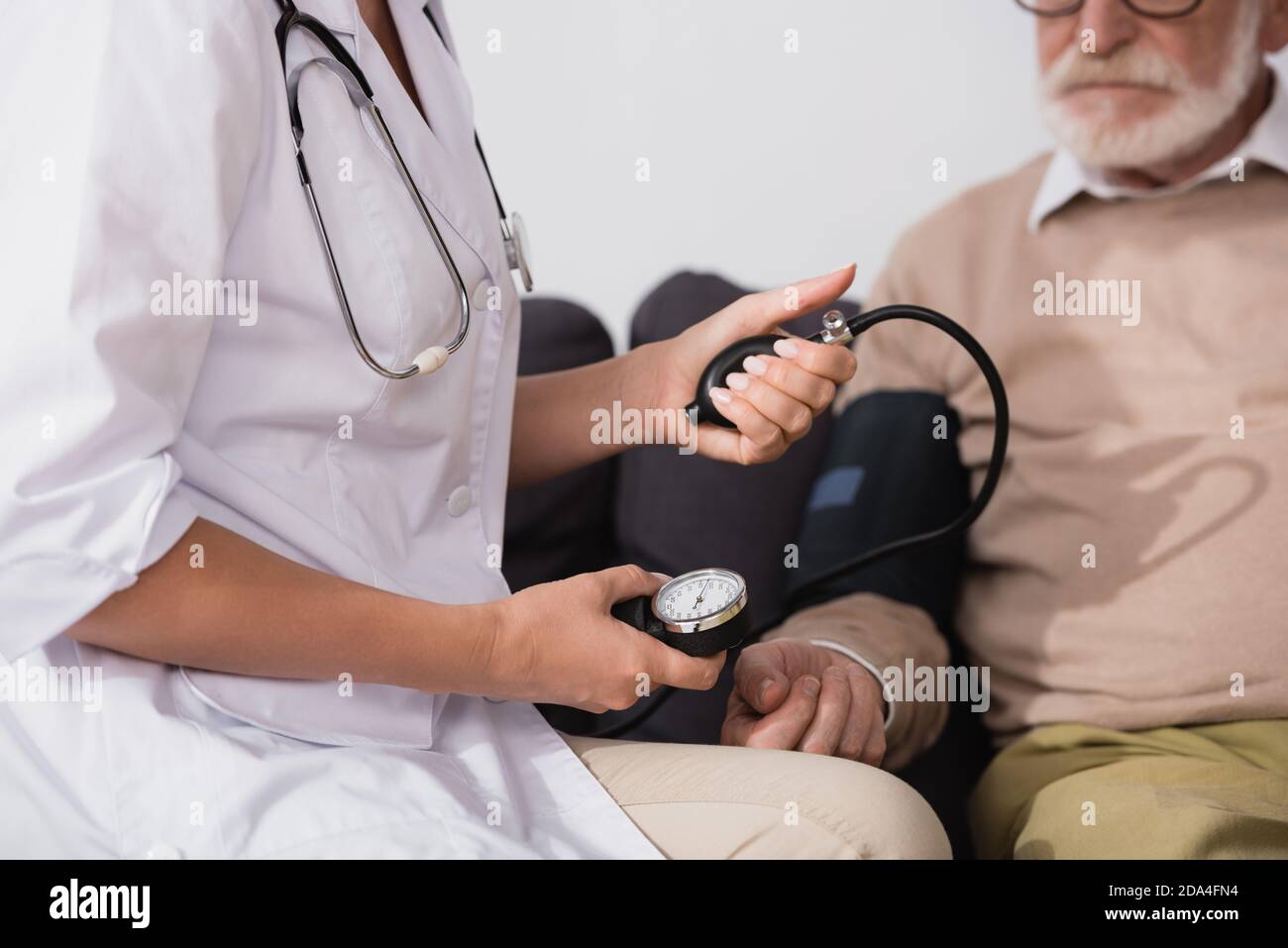 cropped view of geriatric nurse examining elderly patient with stethoscope on blurred background Stock Photo