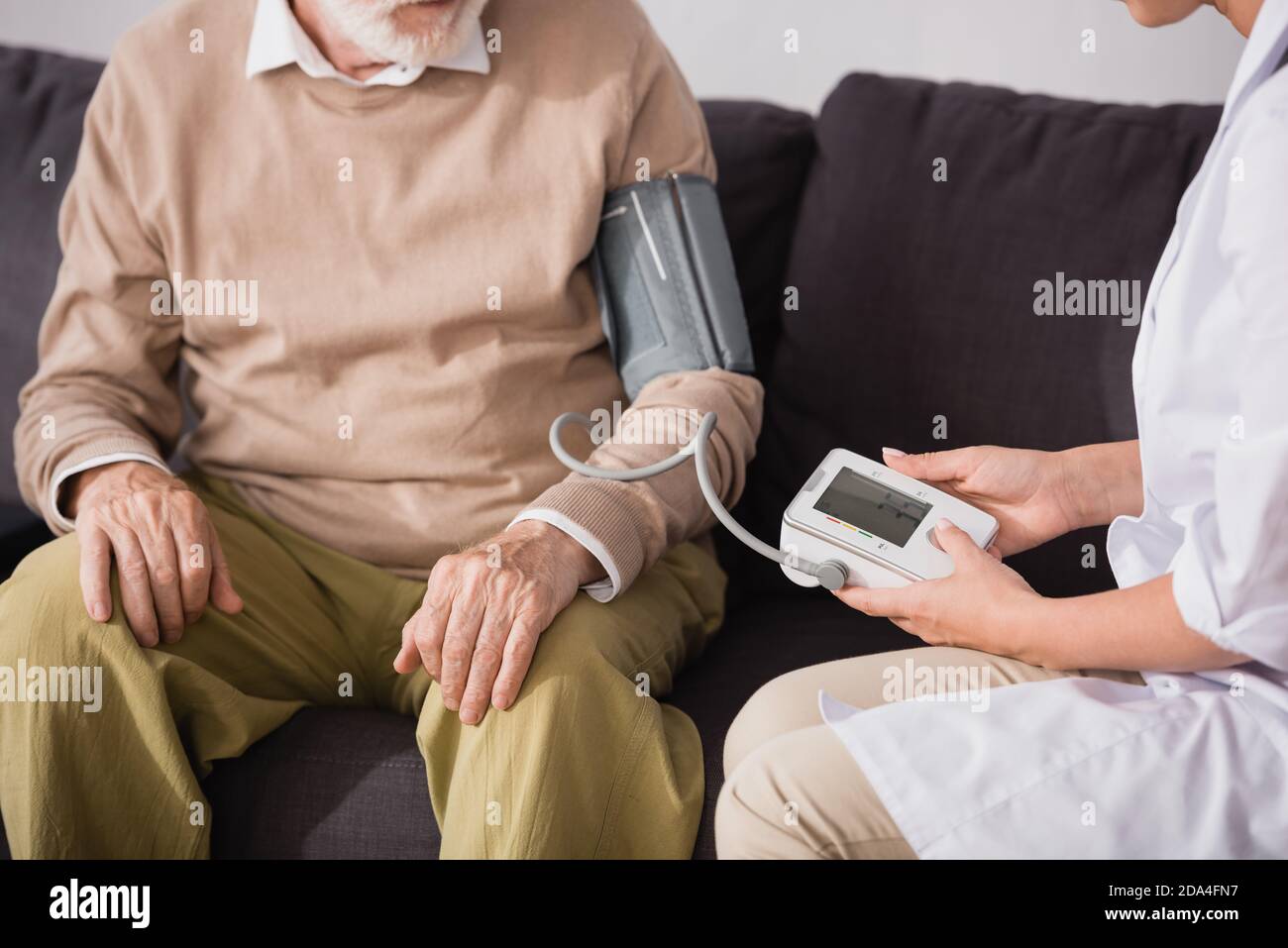 cropped view of geriatric nurse examining aged man with tonometer at home Stock Photo