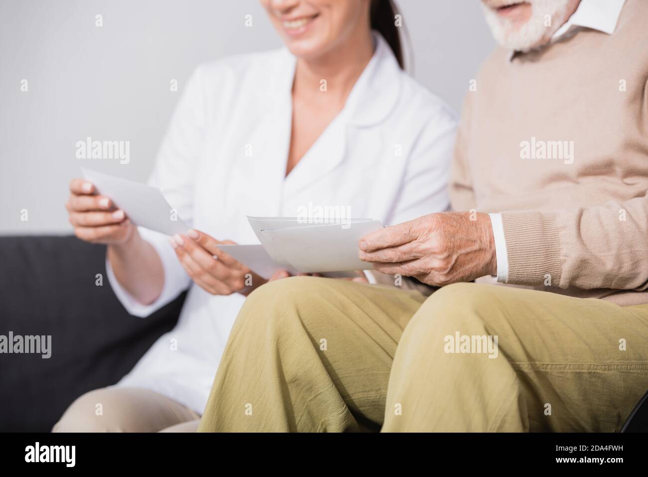social worker showing photos to aged man on blurred background Stock Photo