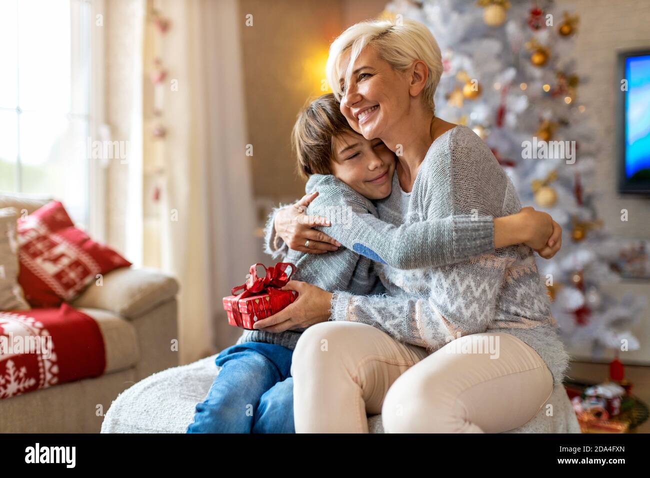 Smiling boy receiving gift from his mother at Christmas Stock Photo