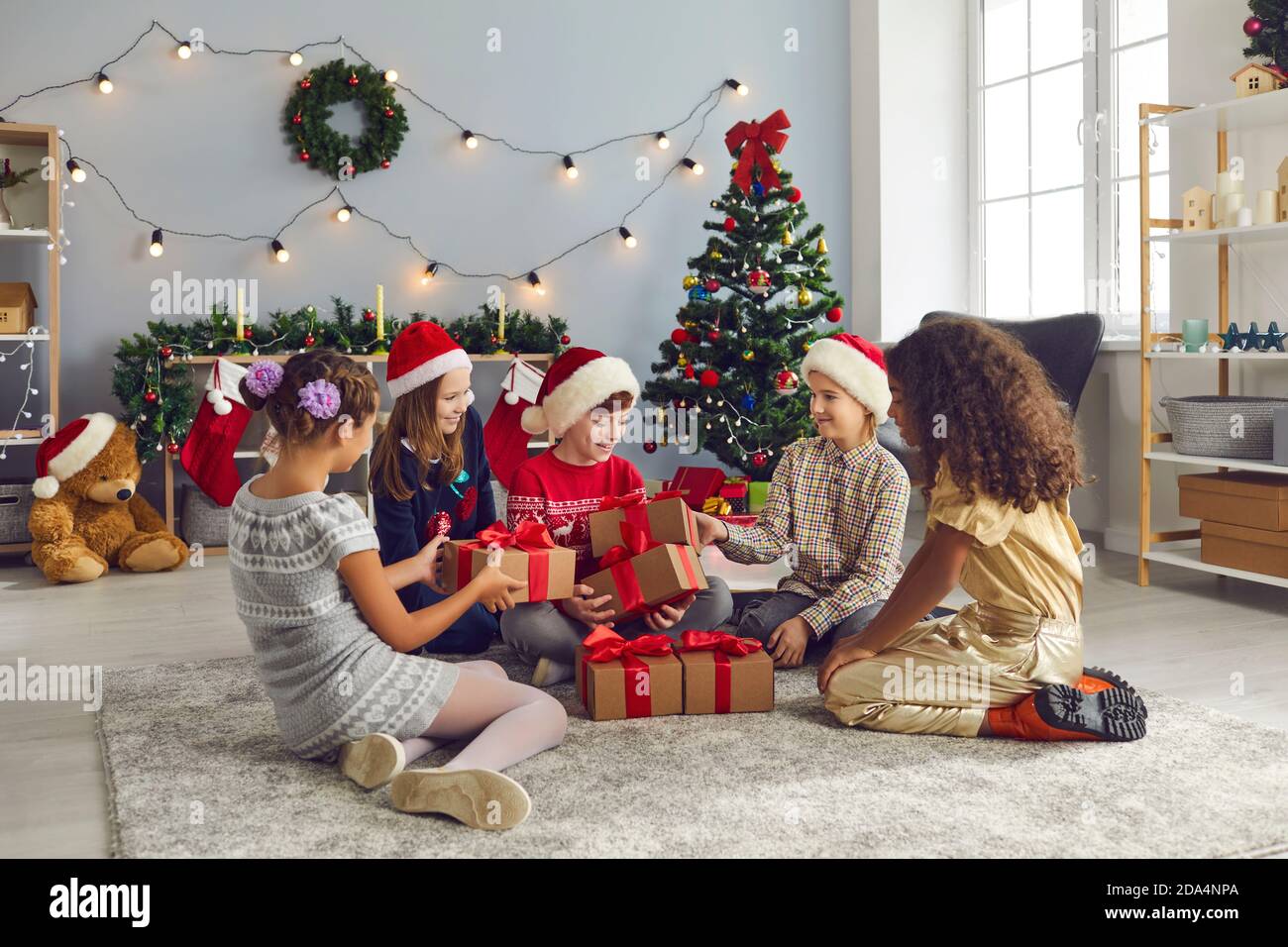 Group of happy mixed race children having home Christmas party and giving presents Stock Photo