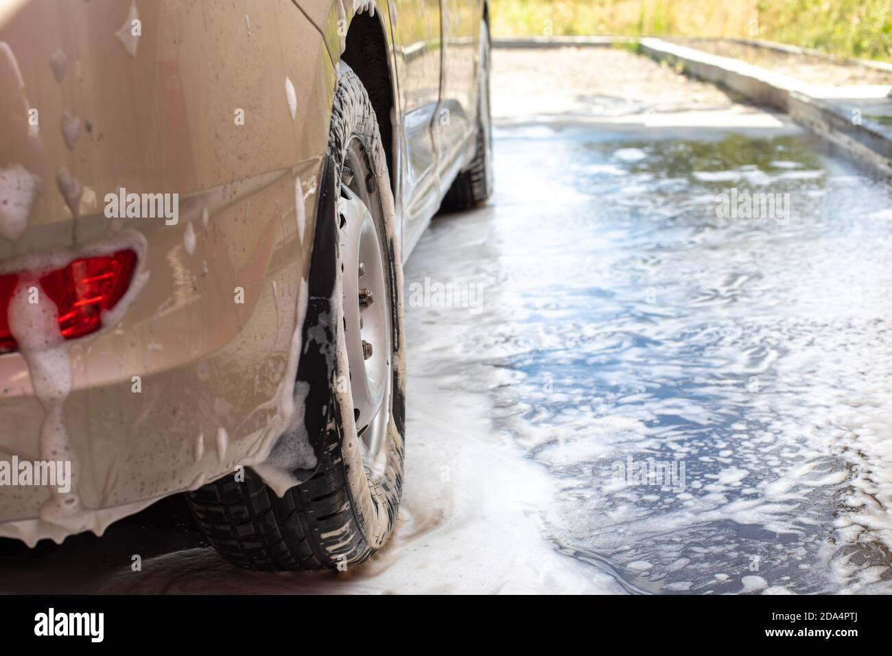 Rear wheel of a passenger car wet from water and shampoo foam, car wash