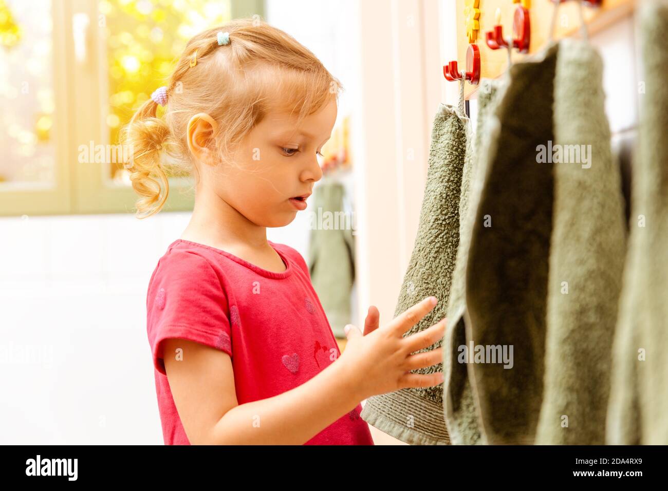 Little girl in nursery school using towel in bathroom Stock Photo