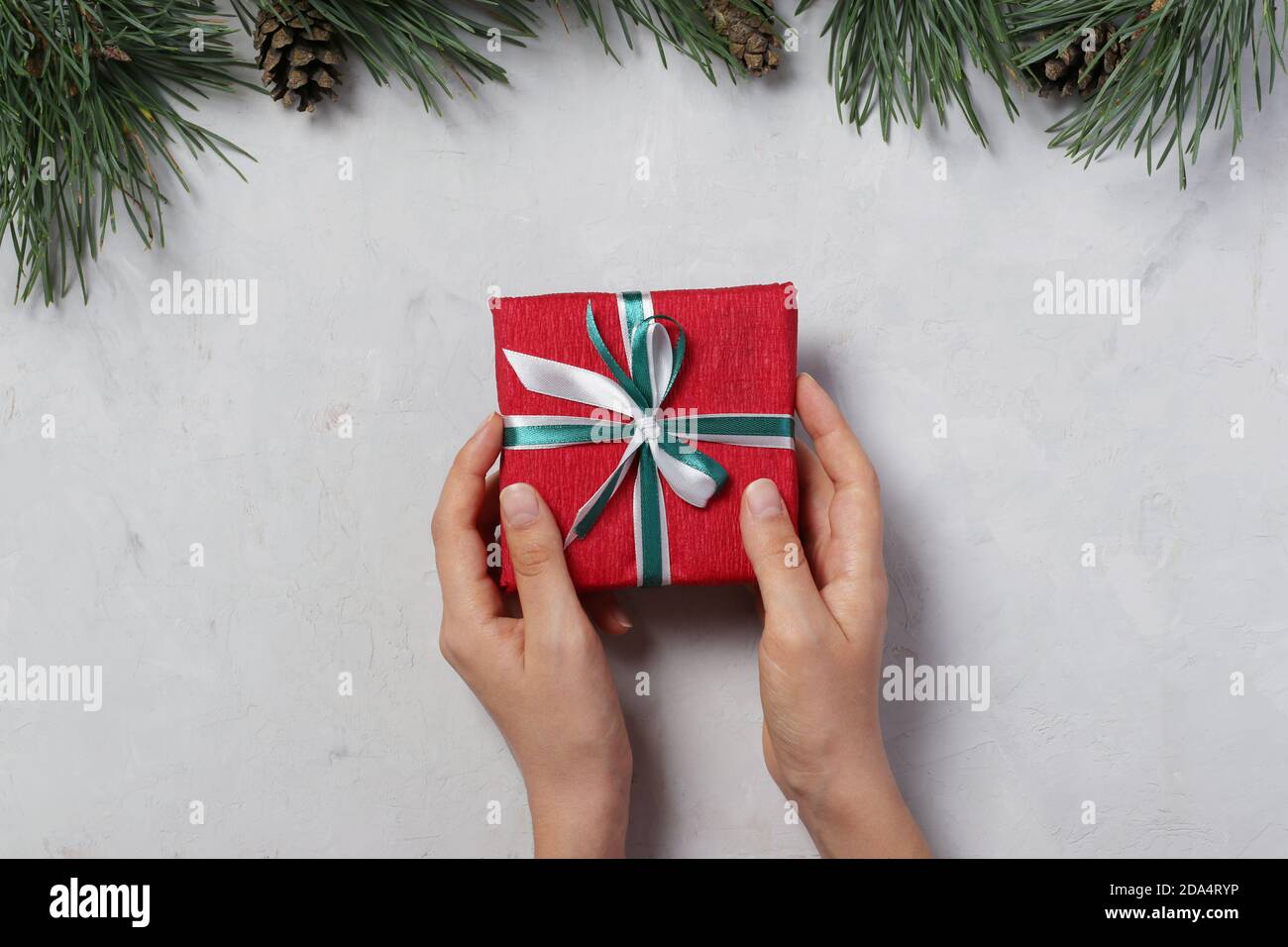 Woman holding red giftbox with ribbons on gray background. Greeting Xmas card. Boxing day. View from above Stock Photo