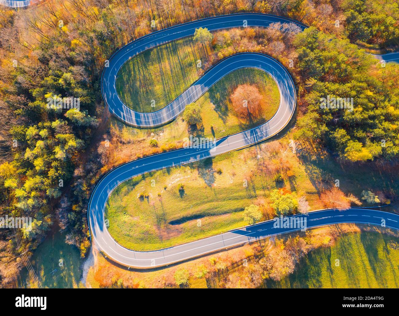 Curvy road up the mountain, aerial view on autumn evening Stock Photo