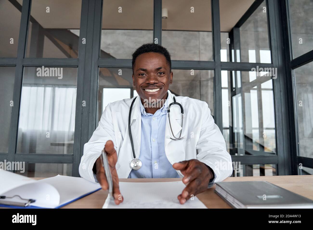 African male doctor talking to camera during telehealth mobile consultation. Stock Photo