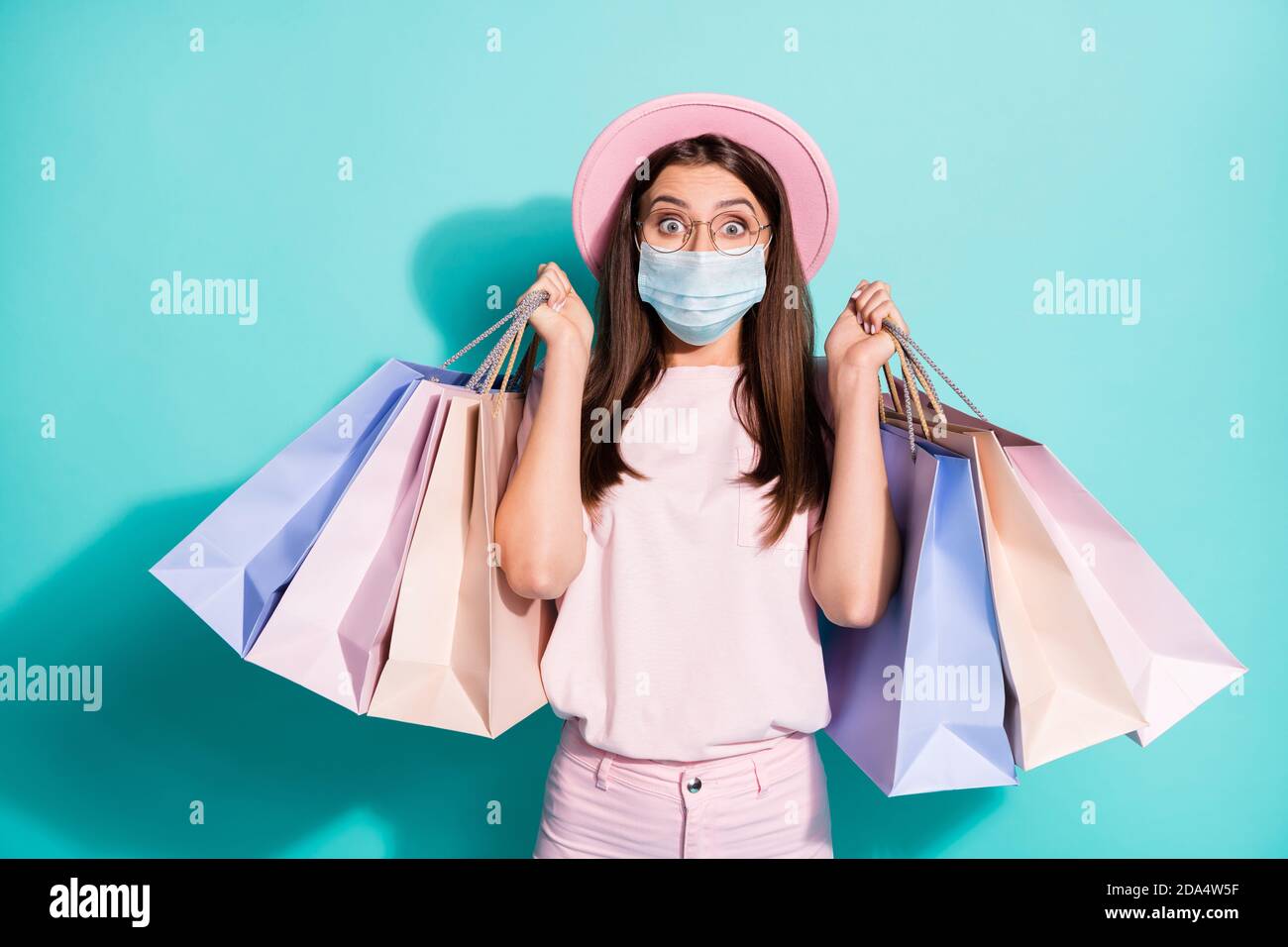 Portrait of delighted girl fashionista carrying bags wear safety mask isolated green turquoise color background Stock Photo