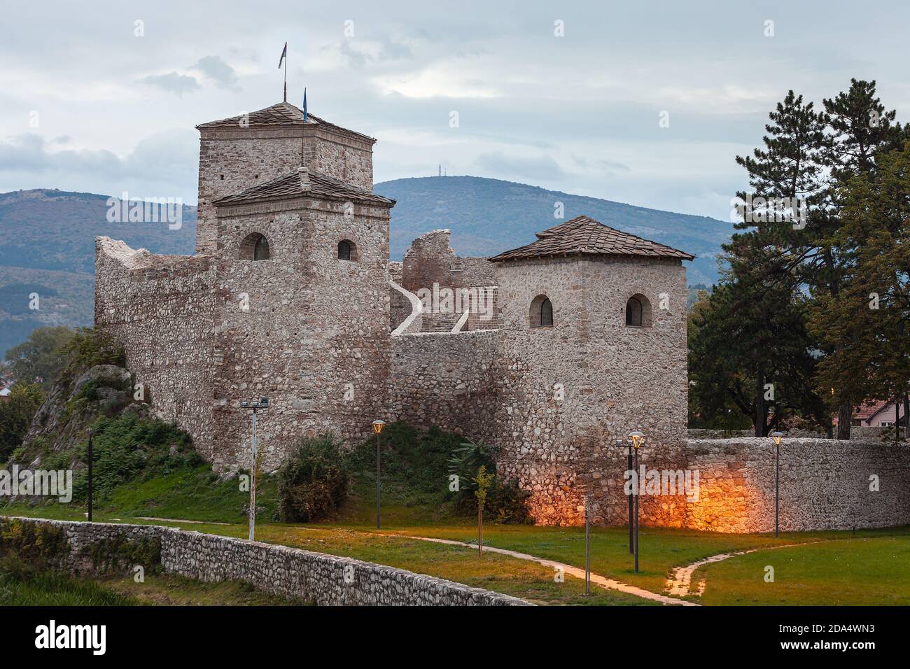 Beautiful, ancient fortress Momcilov grad in Pirot lighten by the lights from the city park with flags at the towers Stock Photo