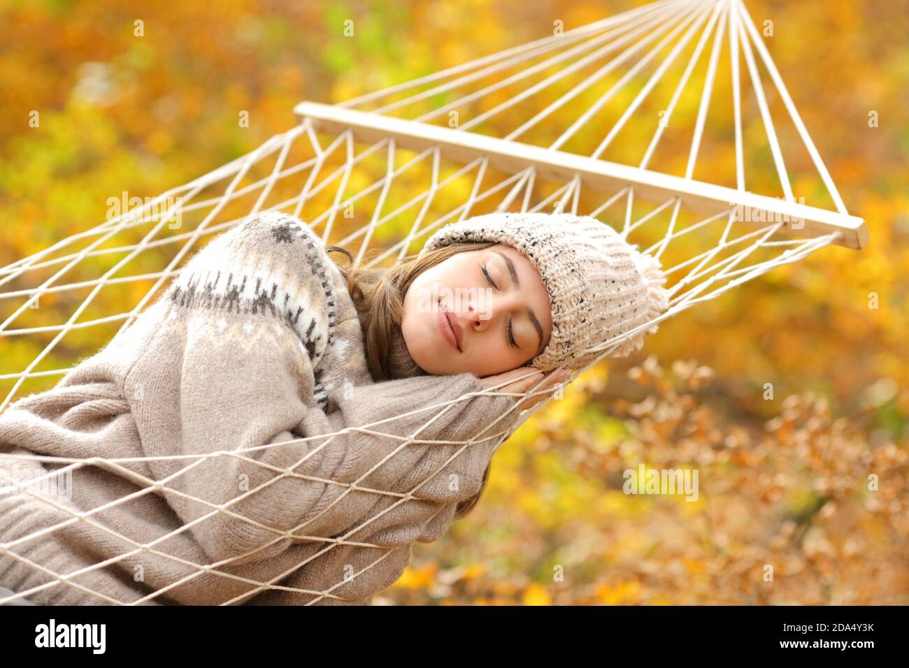 Beauty woman sleeping comfortably on rope hammock in a forest in fall season Stock Photo