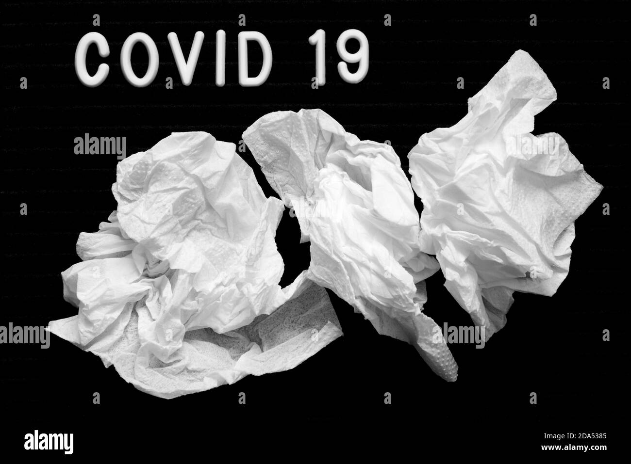 The inscription Covid 19 on a black background, paper napkins, runny nose with coronavirus. Stock Photo