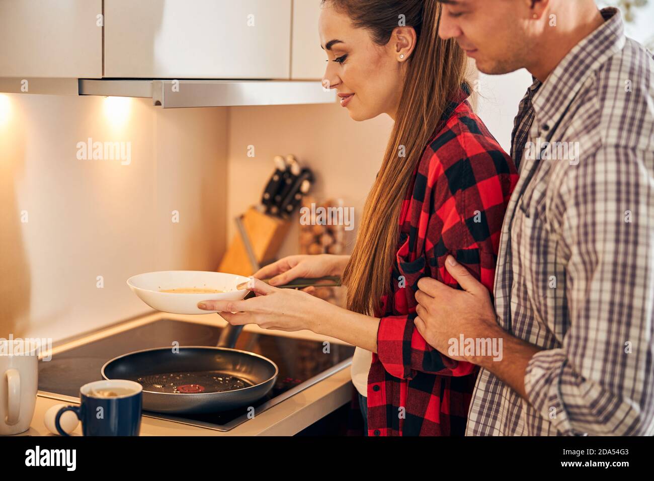 Hungry husband watching her wife making an omelet Stock Photo - Alamy