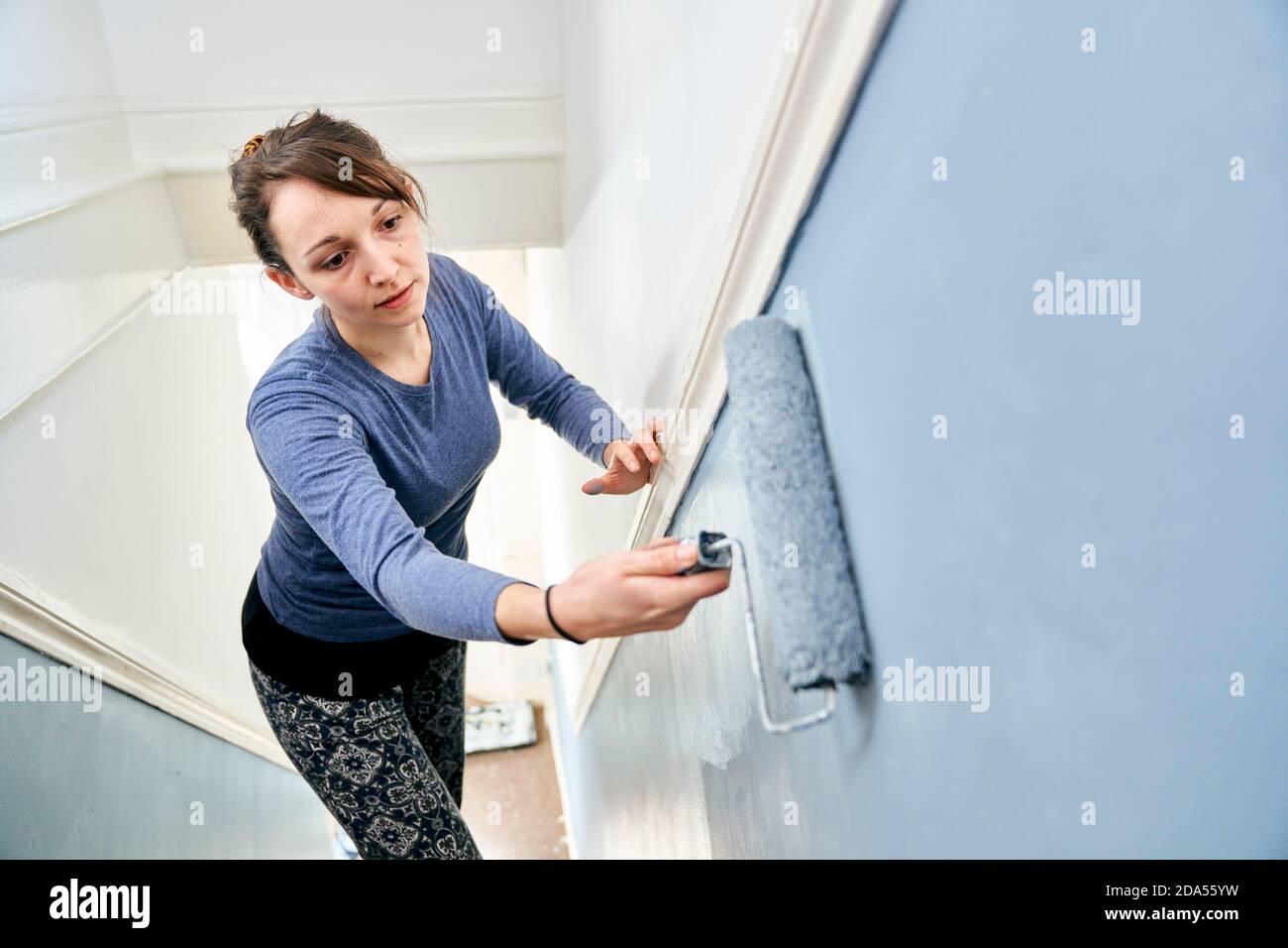 Woman using paint roller to paint staircase Stock Photo