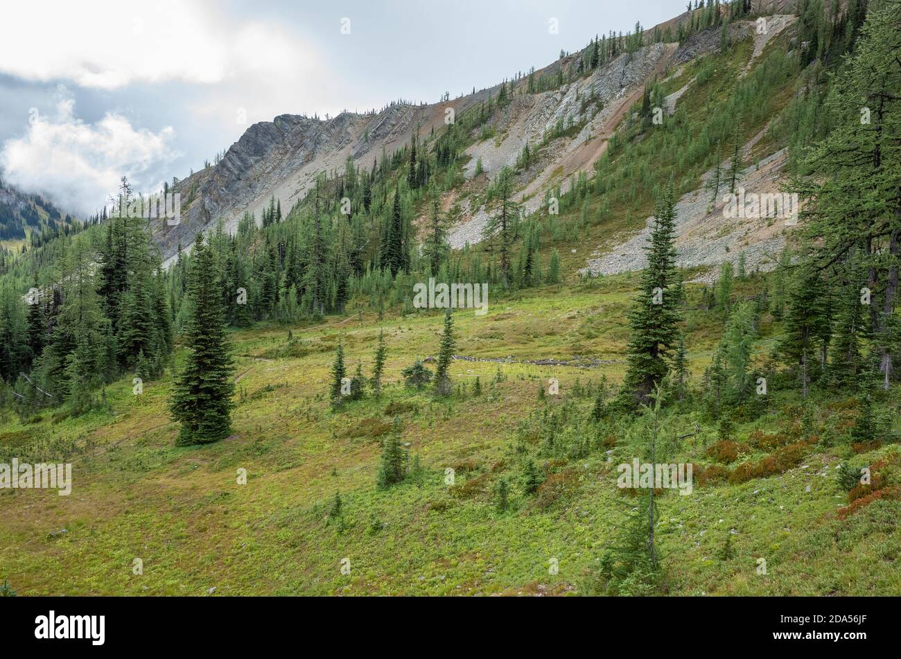 Storm clouds lifting over remote mountain range and alpine meadow Stock ...