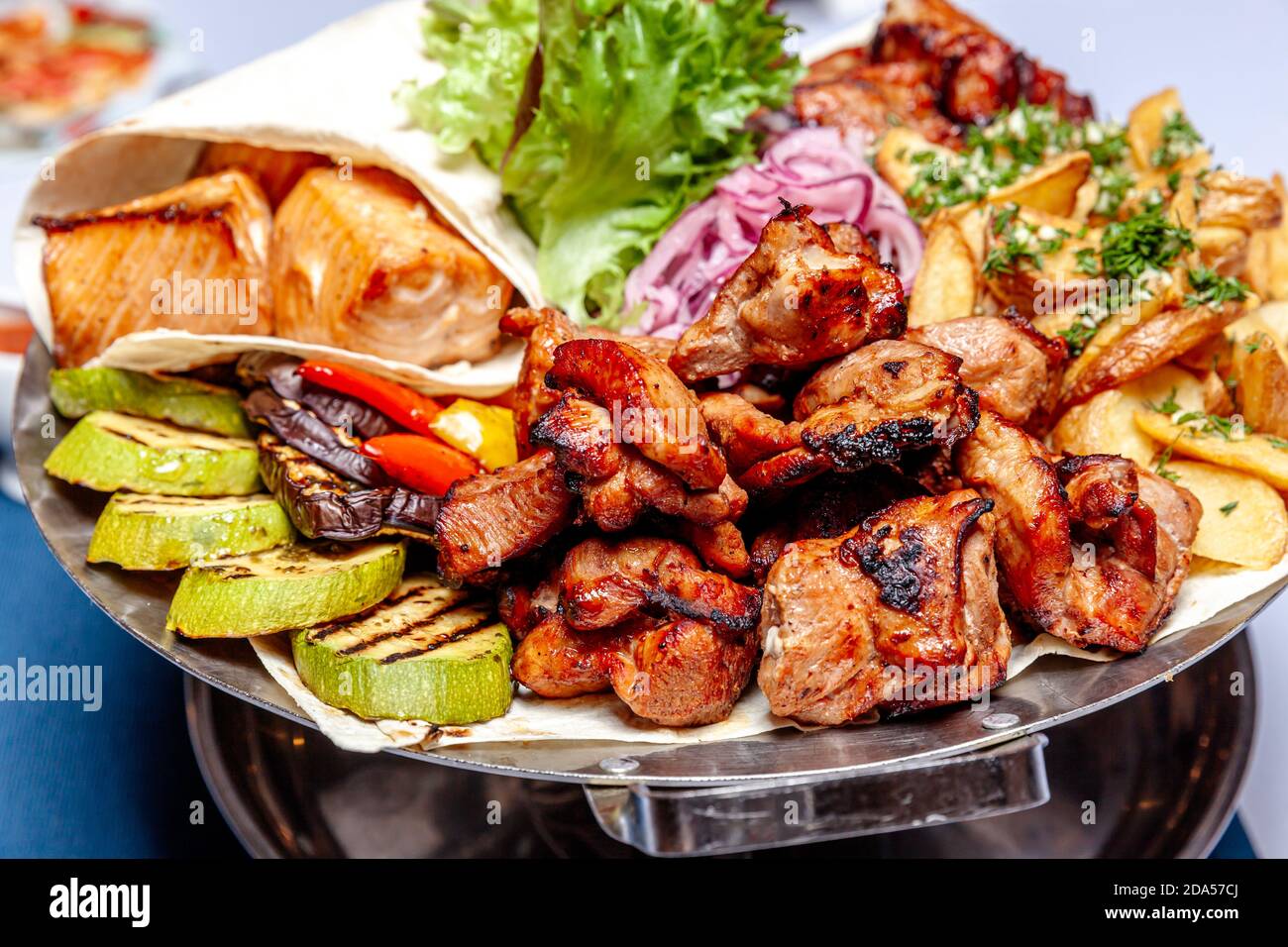 Mixed grill meat fried vegetables and grilled salmon fish fillets  decoration in warm dish. Assorted delicious