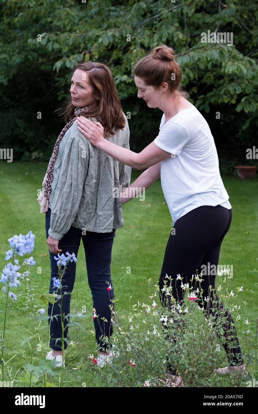 Therapist focussing on the standing posture of a client in a garden. Stock Photo