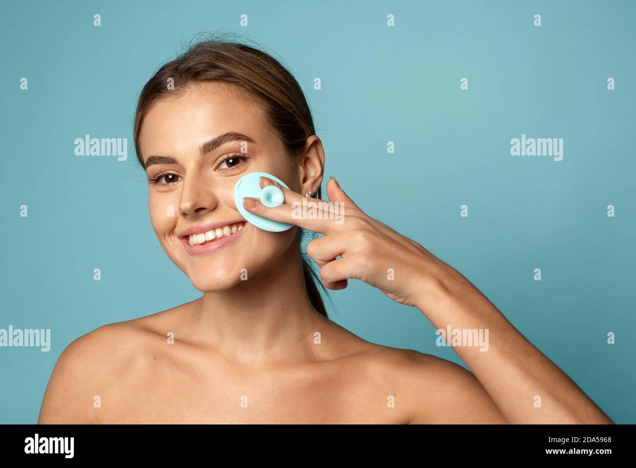 Cleansing the skin with a silicone wash brush. Lovely young woman