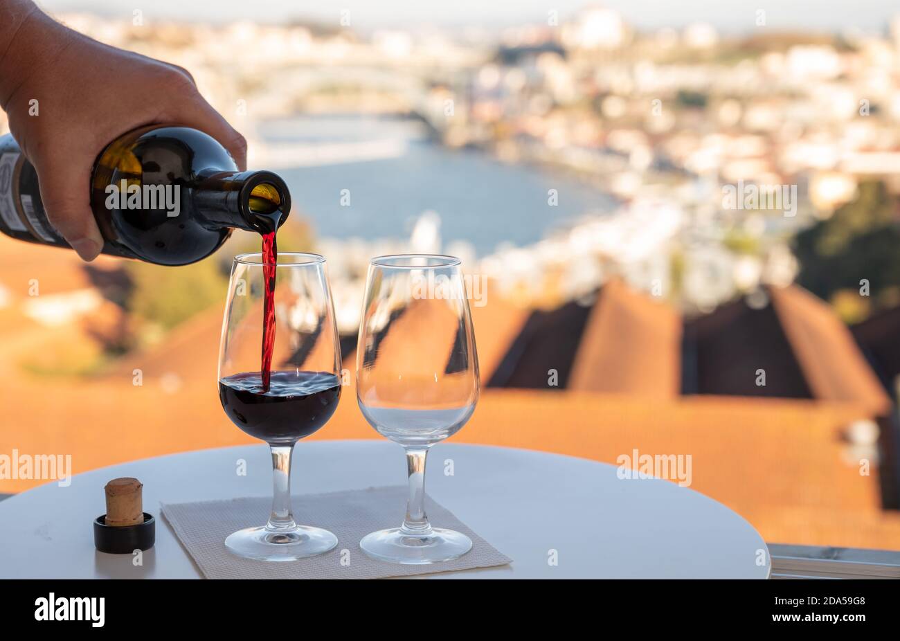 Pouring of fortified dessert ruby, tawny port wines in glasses with view on  Douro river, porto lodges of Vila Nova de Gaia and city of Porto, Portugal  Stock Photo - Alamy