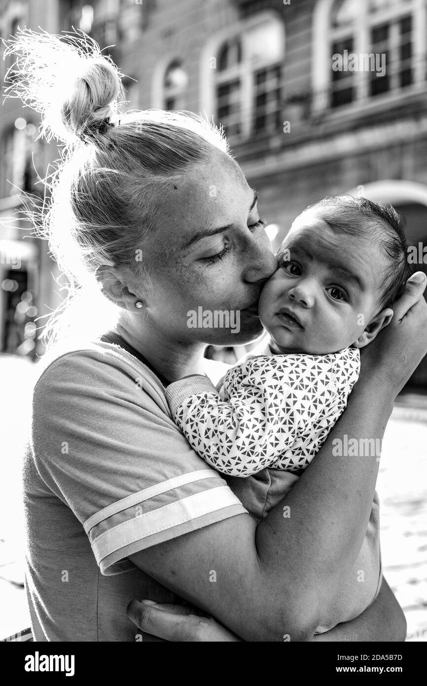 Loving mother - romanian girl hugging her child. Old town.Poznan, Poland. Stock Photo