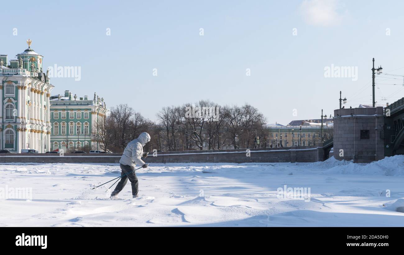 Woman skier riding on ice of the frozen Neva River at sunny day, winter in St.Petersburg, Hermitage on background Stock Photo