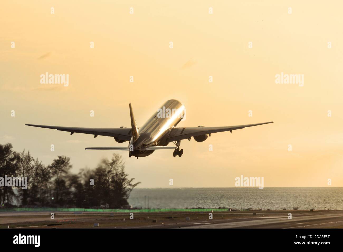 Passenger airplane take off at sunset above the sea. Silhouette of plane fly up . Vacation, aviation, travel concept Stock Photo