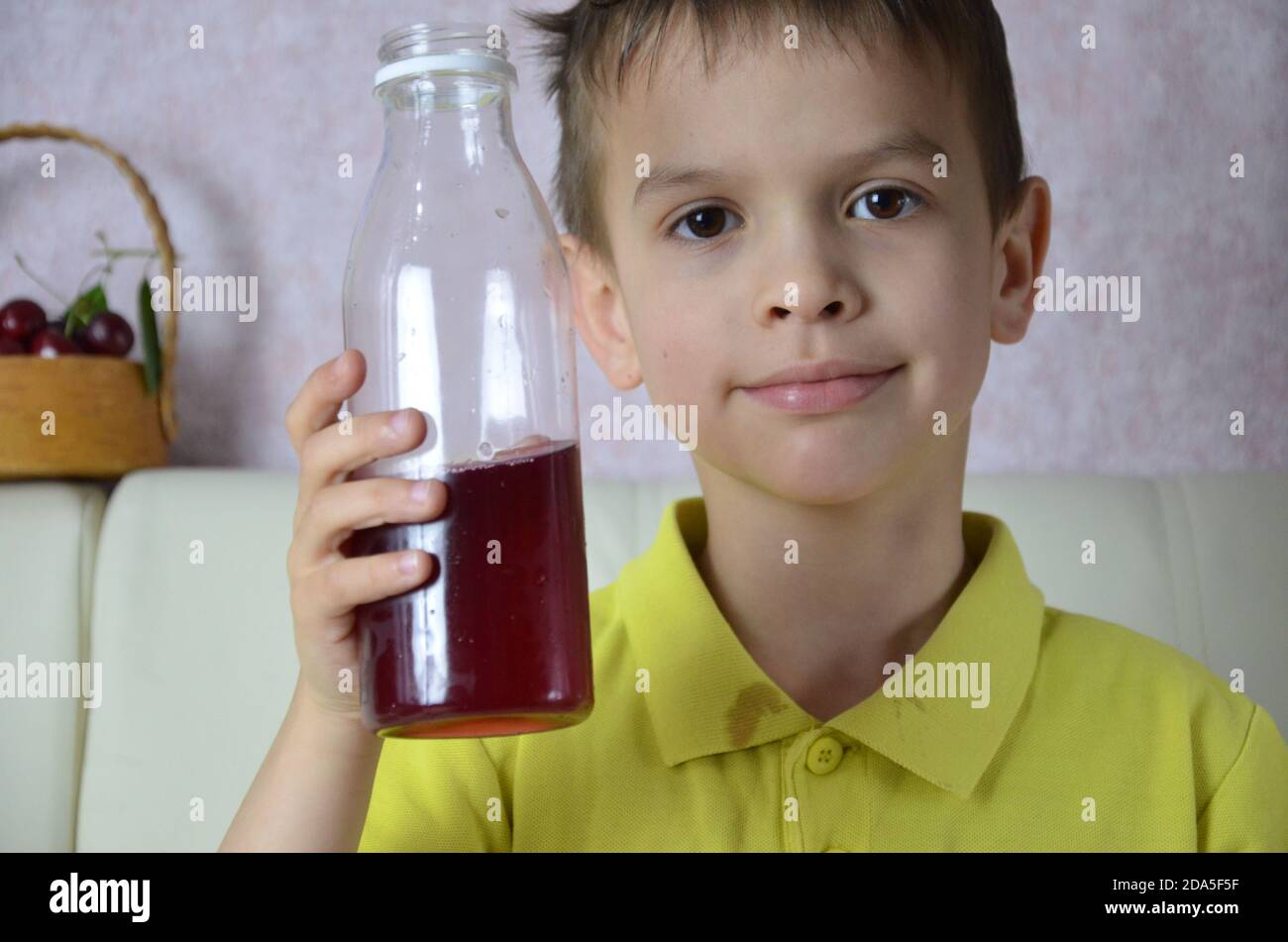 Cute little boy drinking juice at home, cherry juice drinks from a